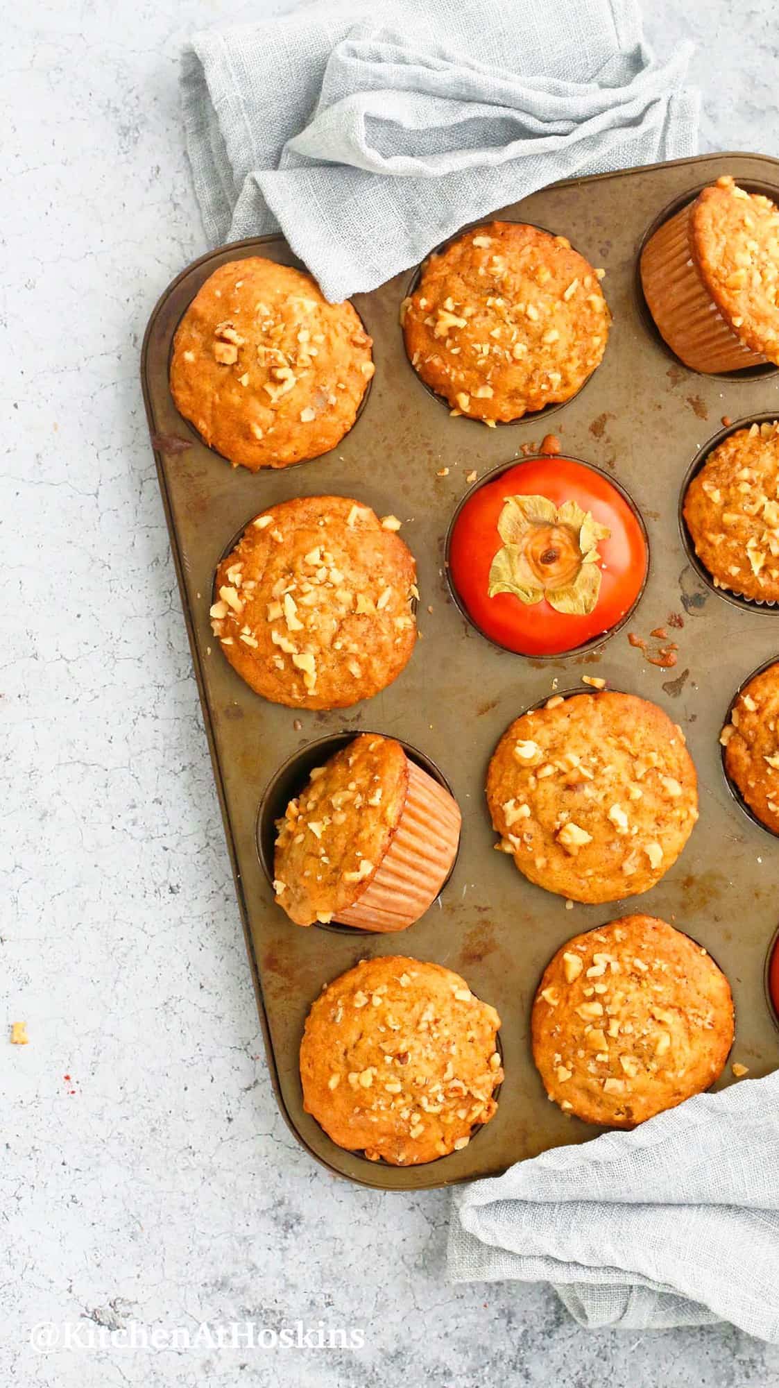 muffin pan with baked persimmon walnut muffins and persimmons.