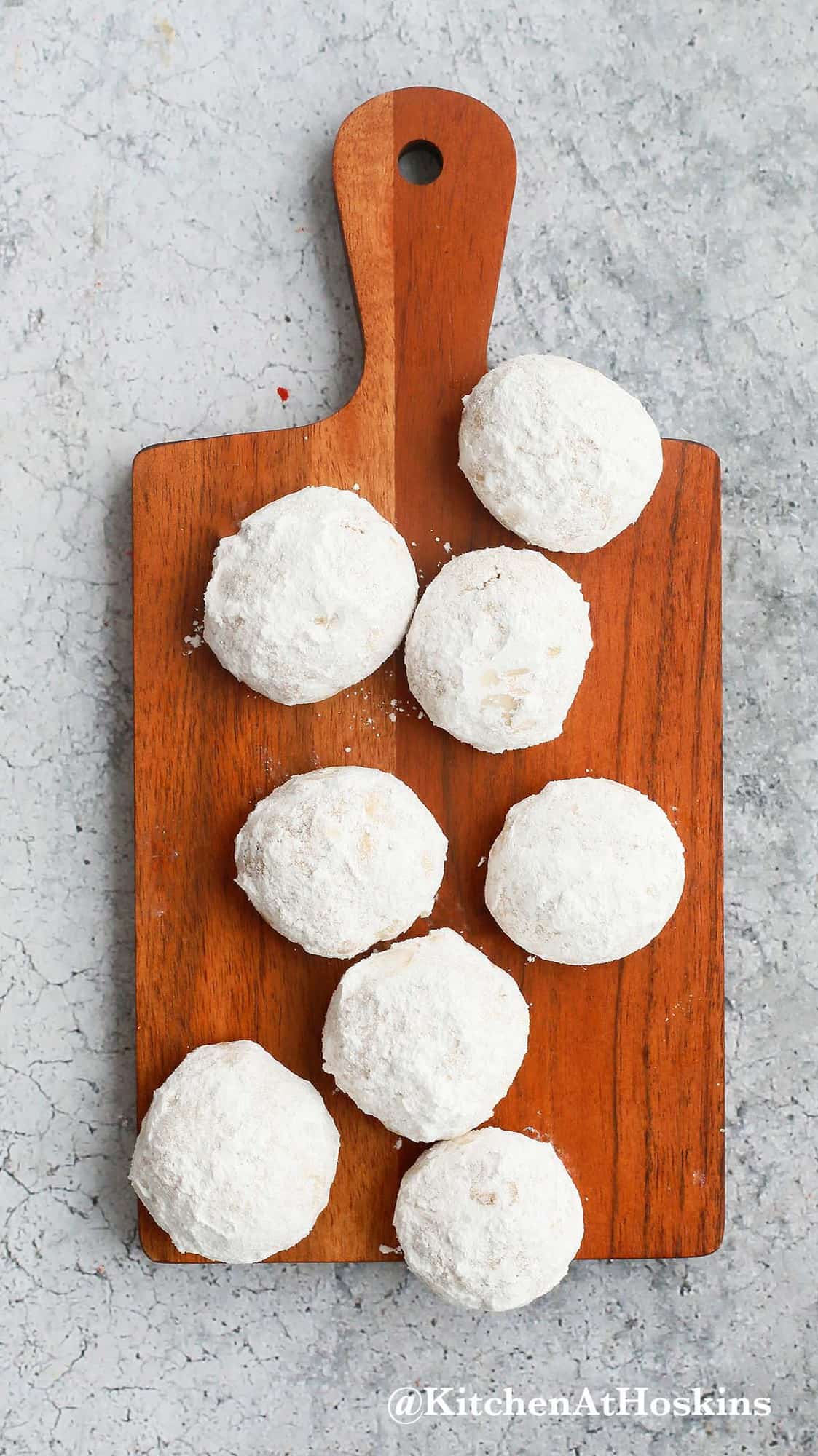 pecan snowball cookies placed on a rectangular  wooden board. 