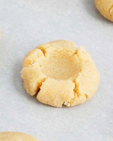 one shaped thumbprint cookie dough on white paper.