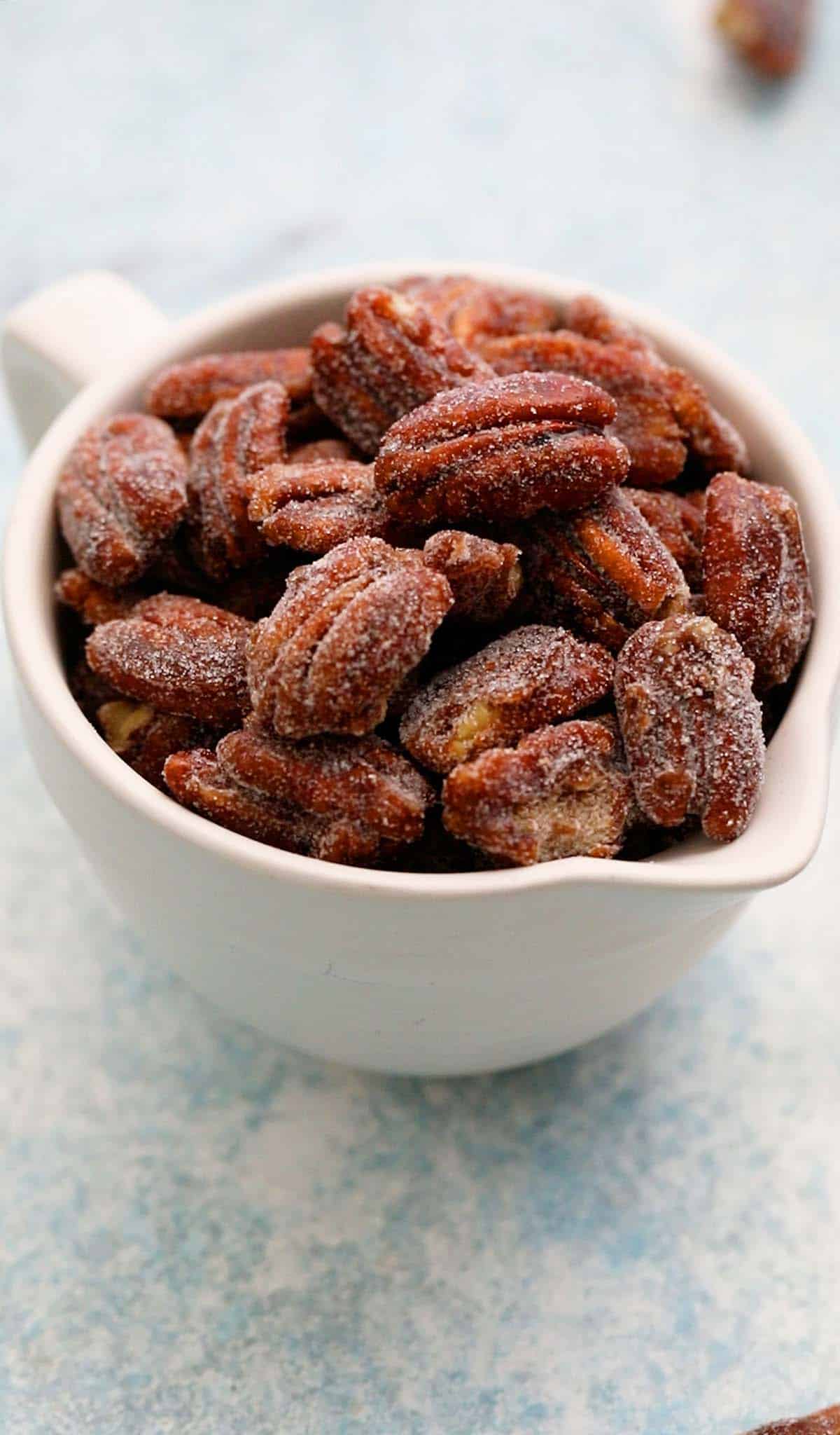 a white ceramic cup filled with candied pecans. 