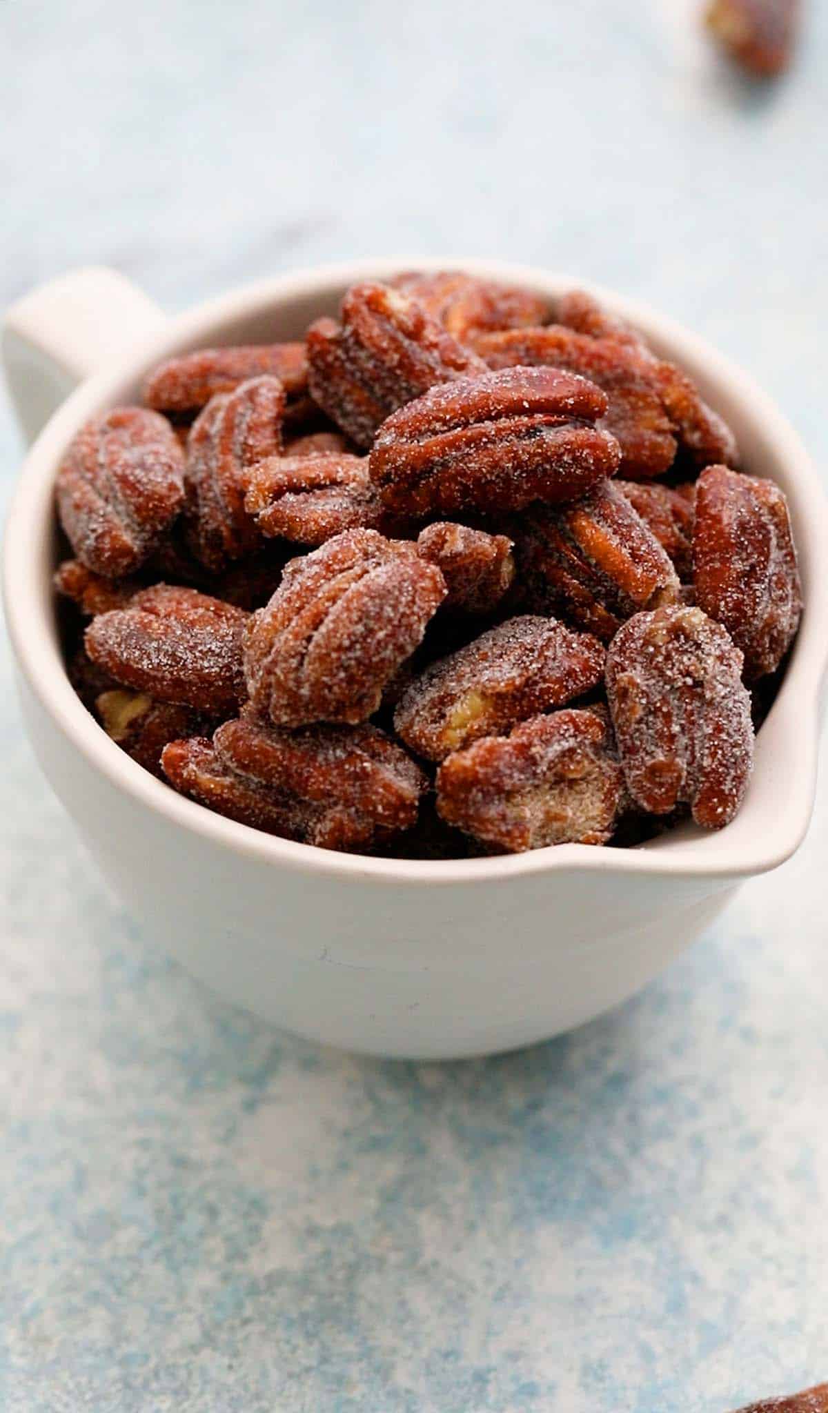 a white ceramic cup filled with candied pecans.