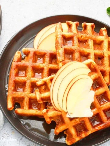 waffles on a plate with apple slices.