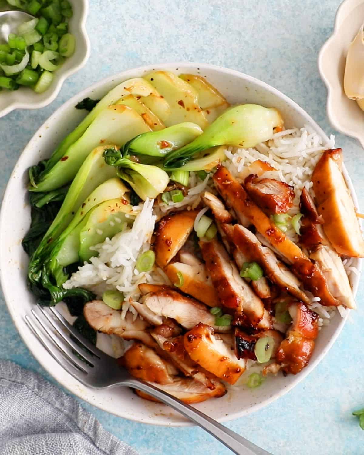 chopped brown teriyaki chicken and green bok choy in a white bowl.
