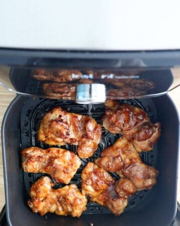 6 teriyaki chicken thighs cooking in a air fryer basket.