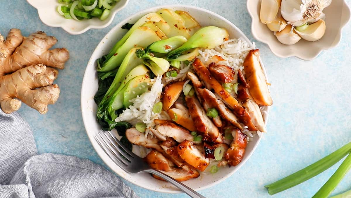 chopped brown teriyaki chicken and green bok choy in a white bowl.