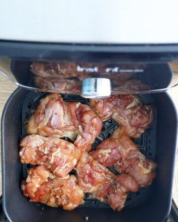 6 teriyaki chicken thighs cooking in a air fryer basket.