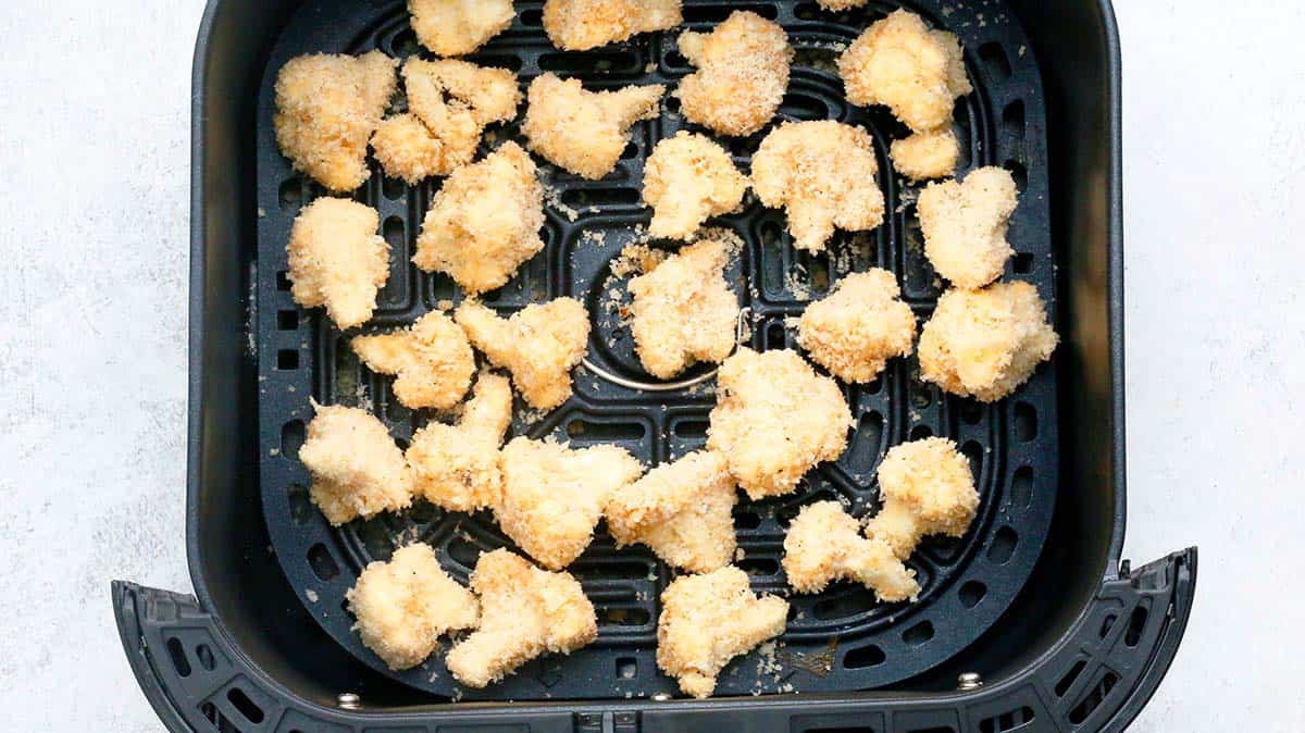 panko coated cauliflower in an air fryer basket.