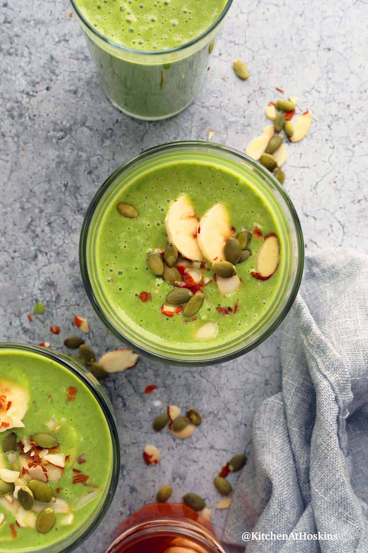 spinach smoothie topped with sliced banana and nuts.