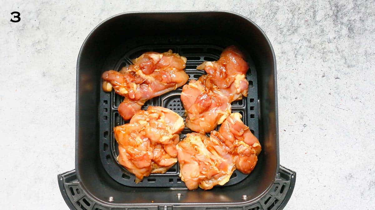 4 boneless chicken thighs in an air fryer basket.