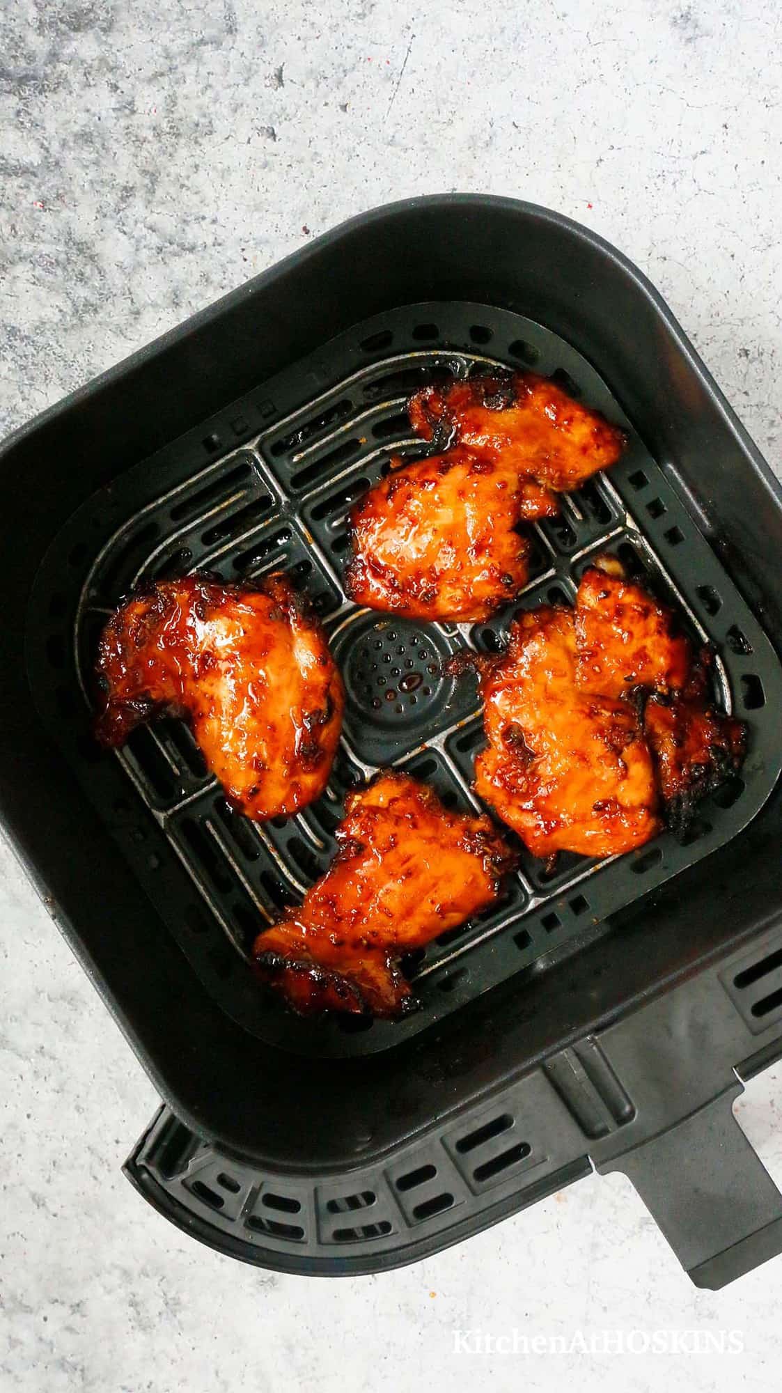 4 teriyaki chicken thighs in an air fryer basket.