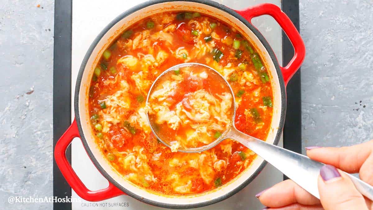 lifting tomato soup with a spoon from a saucepan. 