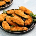 one round black plate filled with stuffed jalapeno poppers.