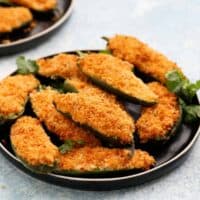 one round black plate filled with stuffed jalapeno poppers.