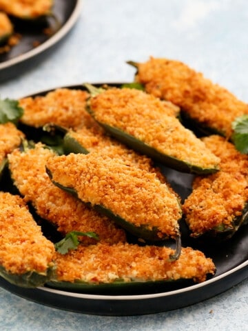 one round black plate filled with stuffed jalapeno poppers.