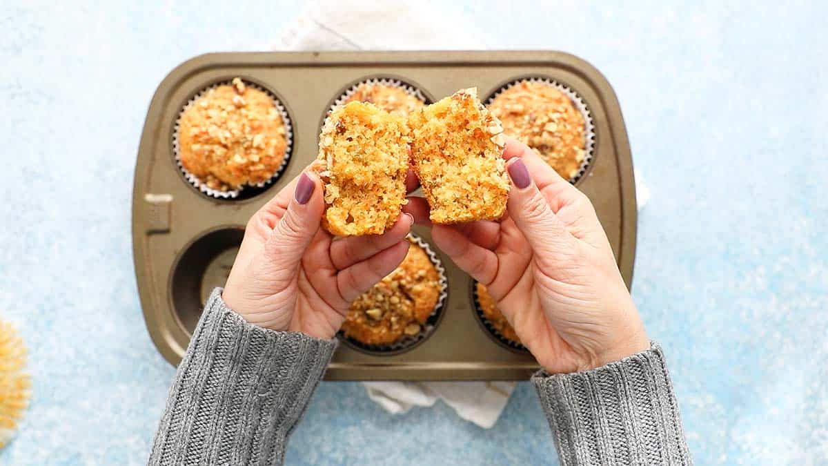 two hands holding a split carrot muffin.