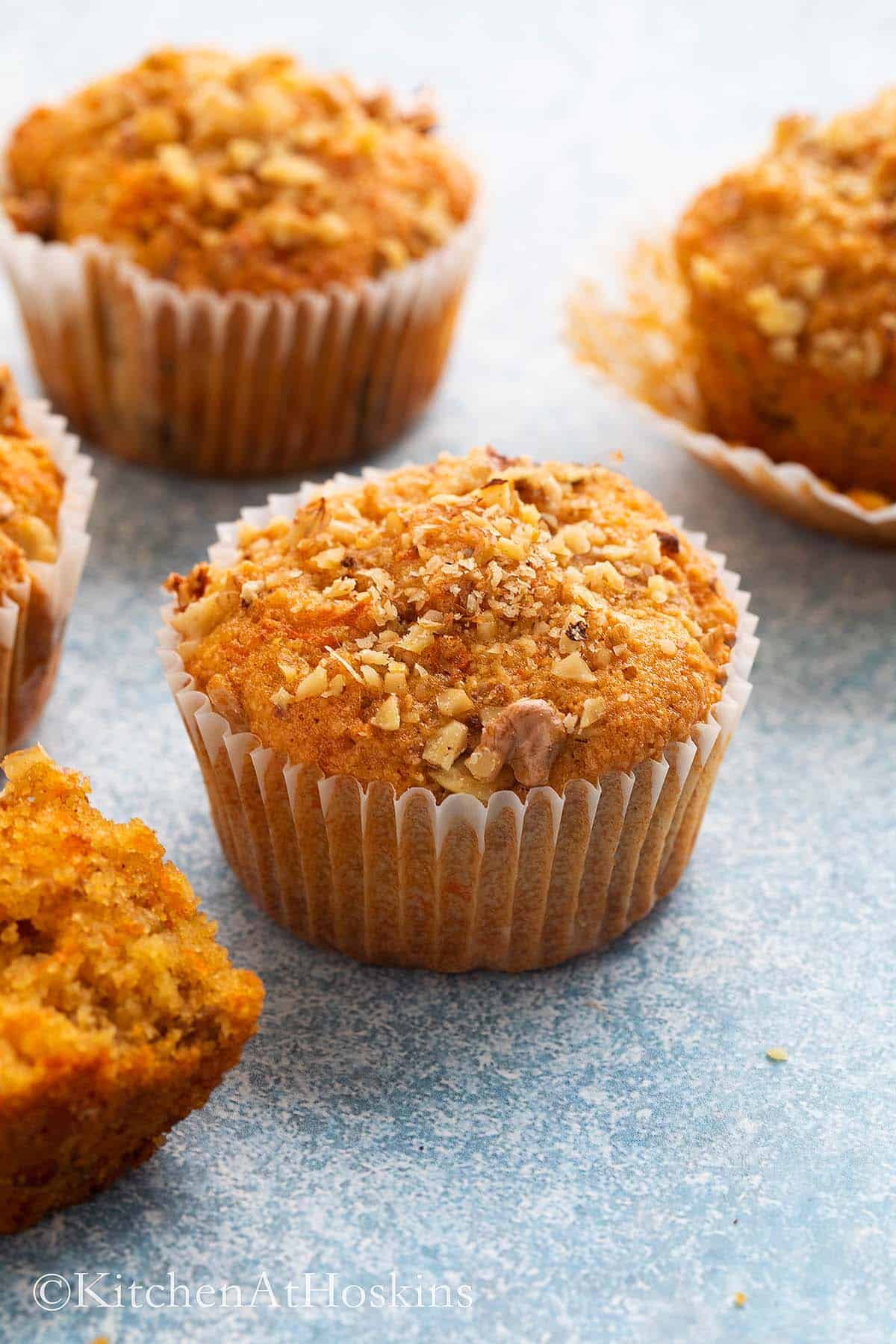 4 baked carrot muffins on a blue board.