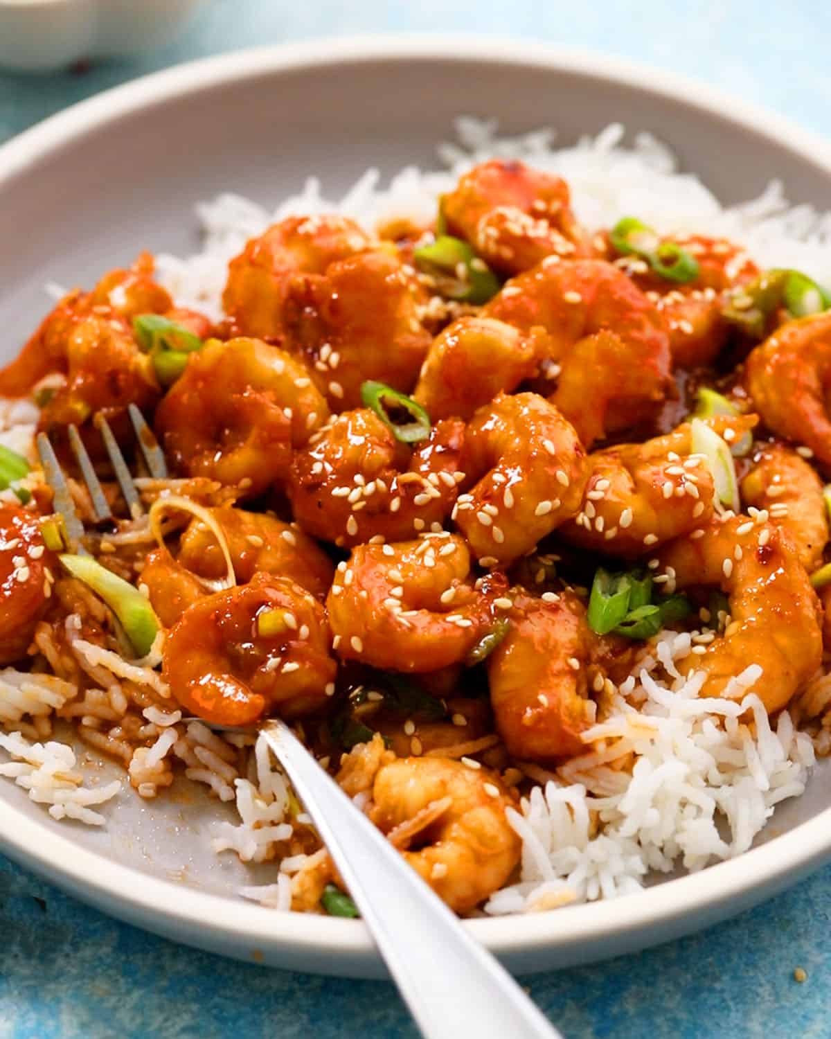 stir fried firecracker shrimp over white rice in a round plate.