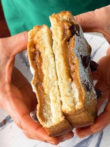 two hands holding a cut peanut butter toast.
