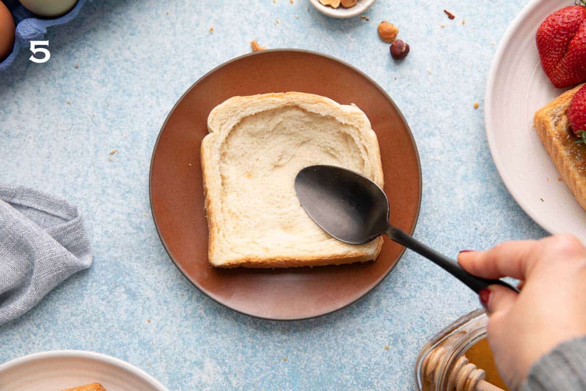 pressing a slice of bread with a black spoon on a small brown plate. 
