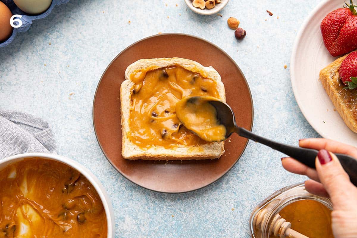 spreading peanut butter filling on a white bread using a black spoon.