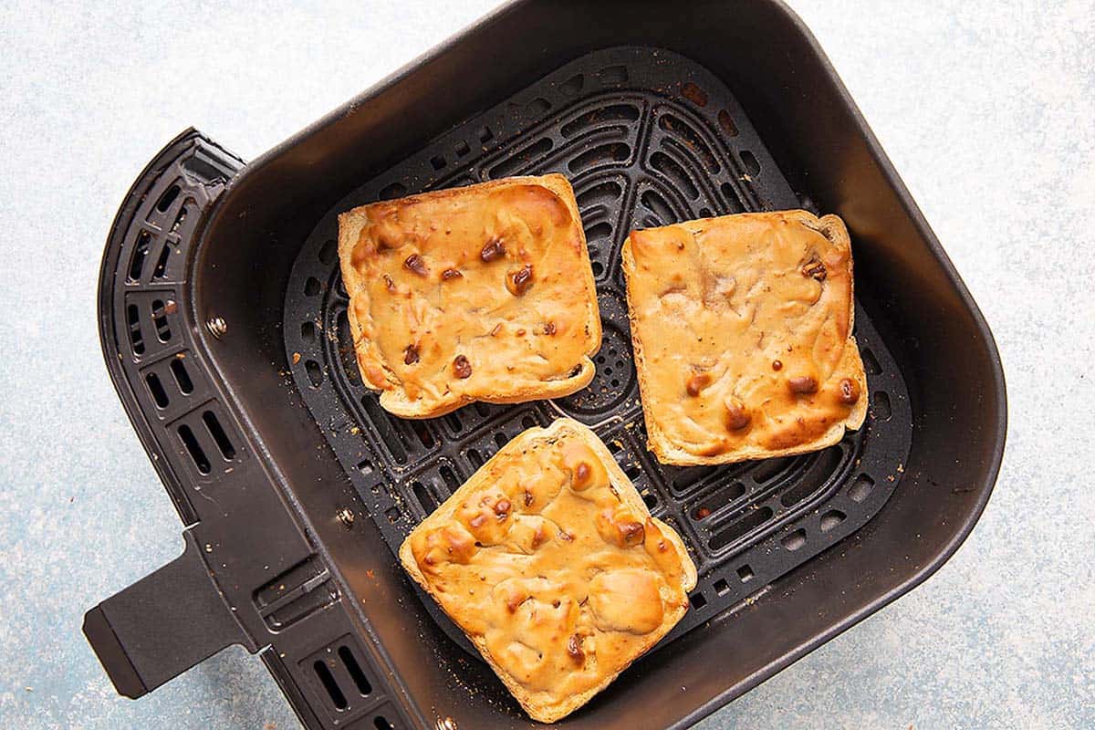 3 peanut butter toasts in a air fryer basket.