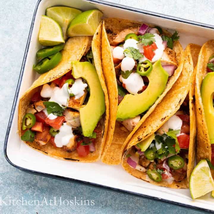 assembled chicken tacos in a white platter.