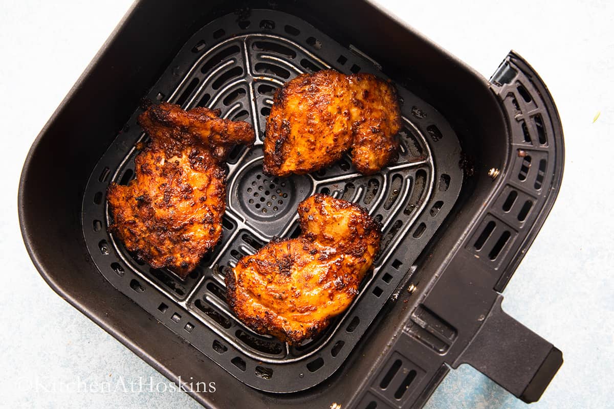 cooked taco chicken thighs in air fryer basket. 