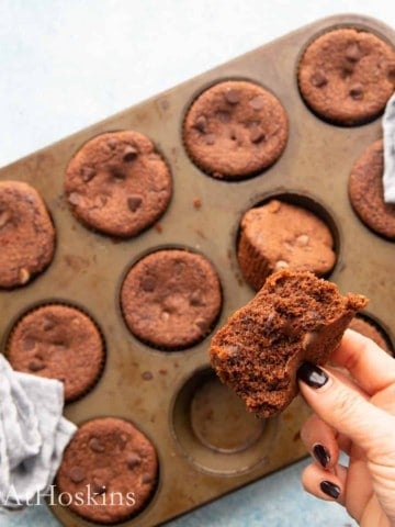 a hand holding a cut chocolate muffin.