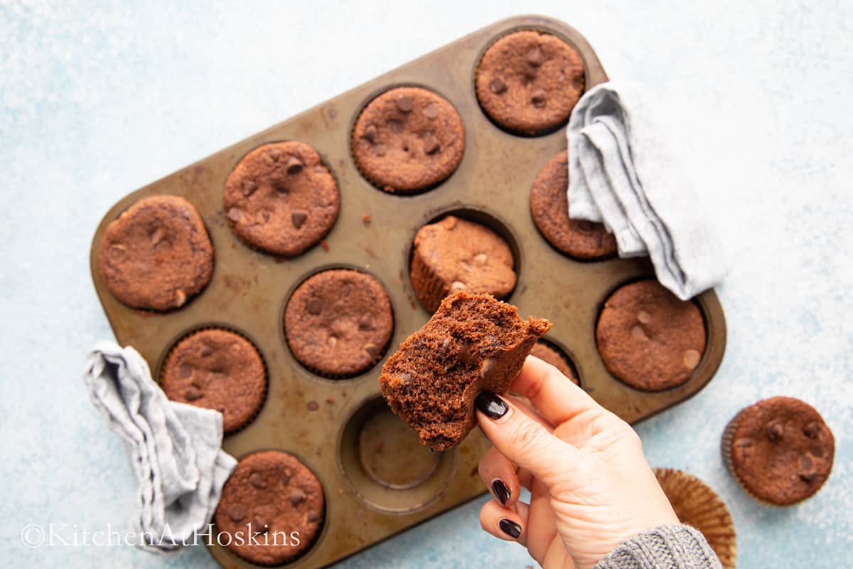 a hand holding a cut almond chocolate muffin. 