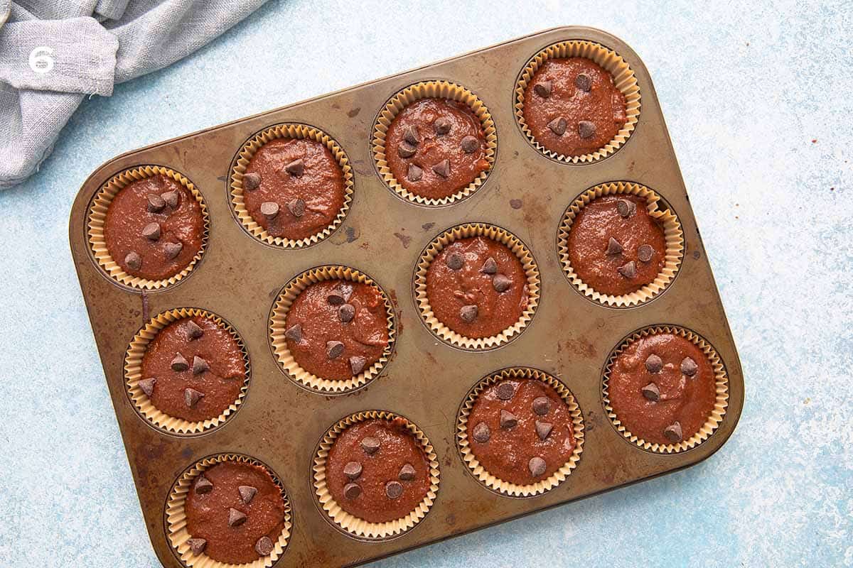 muffin pan with filled chocolate muffin batter. 