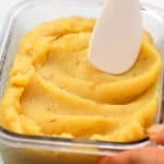 yellow colored badam halwa in a glass dish.