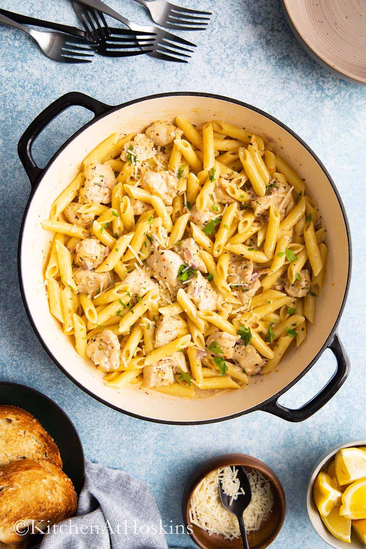 cast iron pan with creamy lemon chicken pasta garnished with parsley.