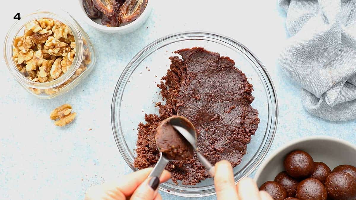 two hands scooping brown dough from a tablespoon. 