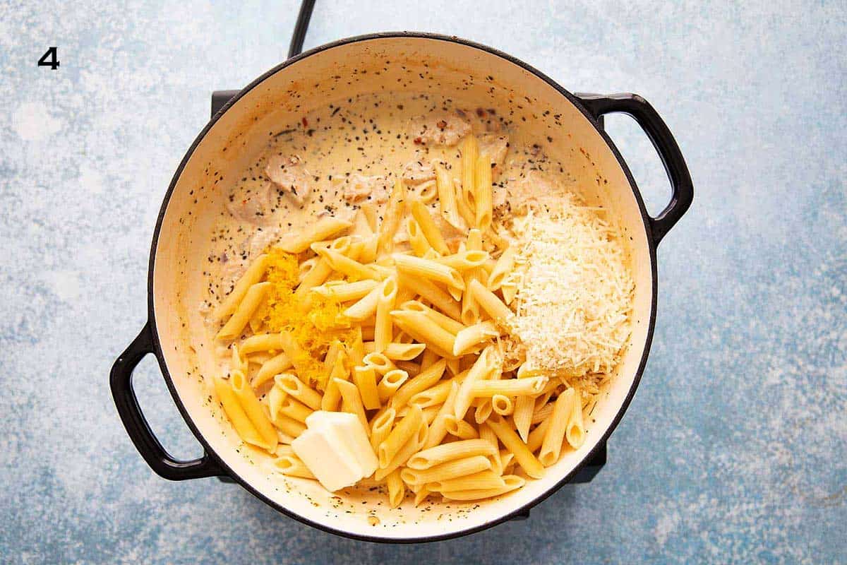 large white skillet with cooked pasta, butter, parmesan and white sauce.
