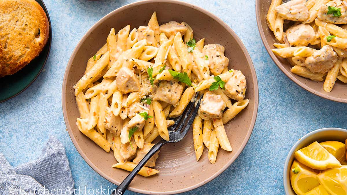 lemon chicken pasta in a brown shallow bowl along with a black fork.