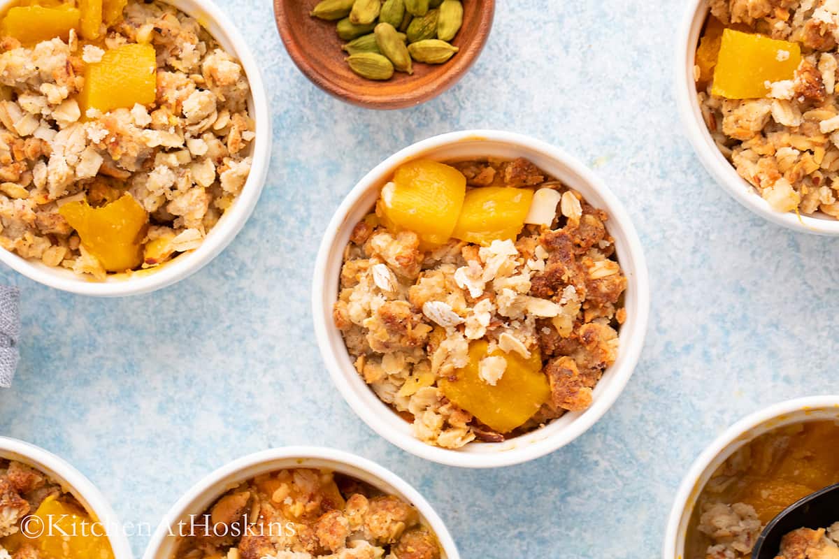 white ramekins with mango oatmeal crisp.