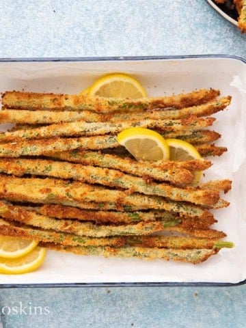 air fried asparagus in a white tray with lemon.