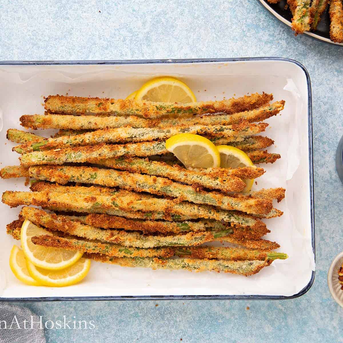 air fried asparagus in a white tray with lemon.