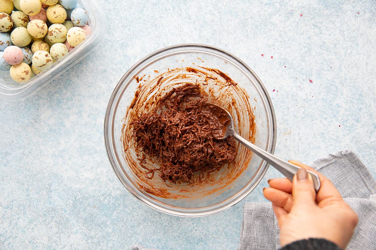 mixing shredded coconut and melted chocolate in a bowl. 