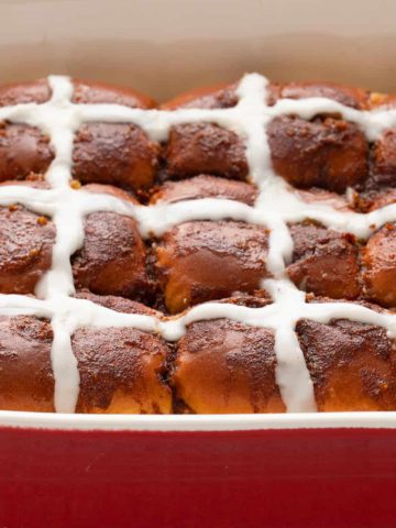 hot cross buns in a red baking dish.