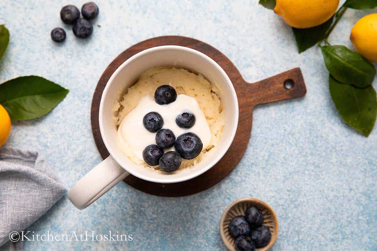 mug with eggless cake topped with blueberries. 