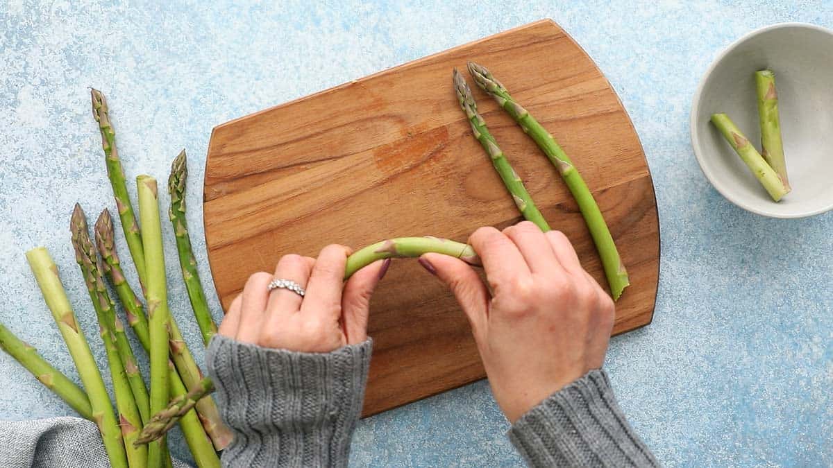 two hands bending one asparagus to snap.