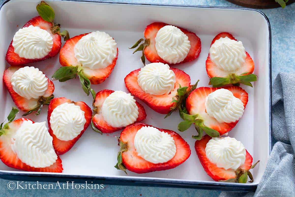 WHITYE TRAY WITH STRAWBERRIES TOPPED WITH CREAM. 
