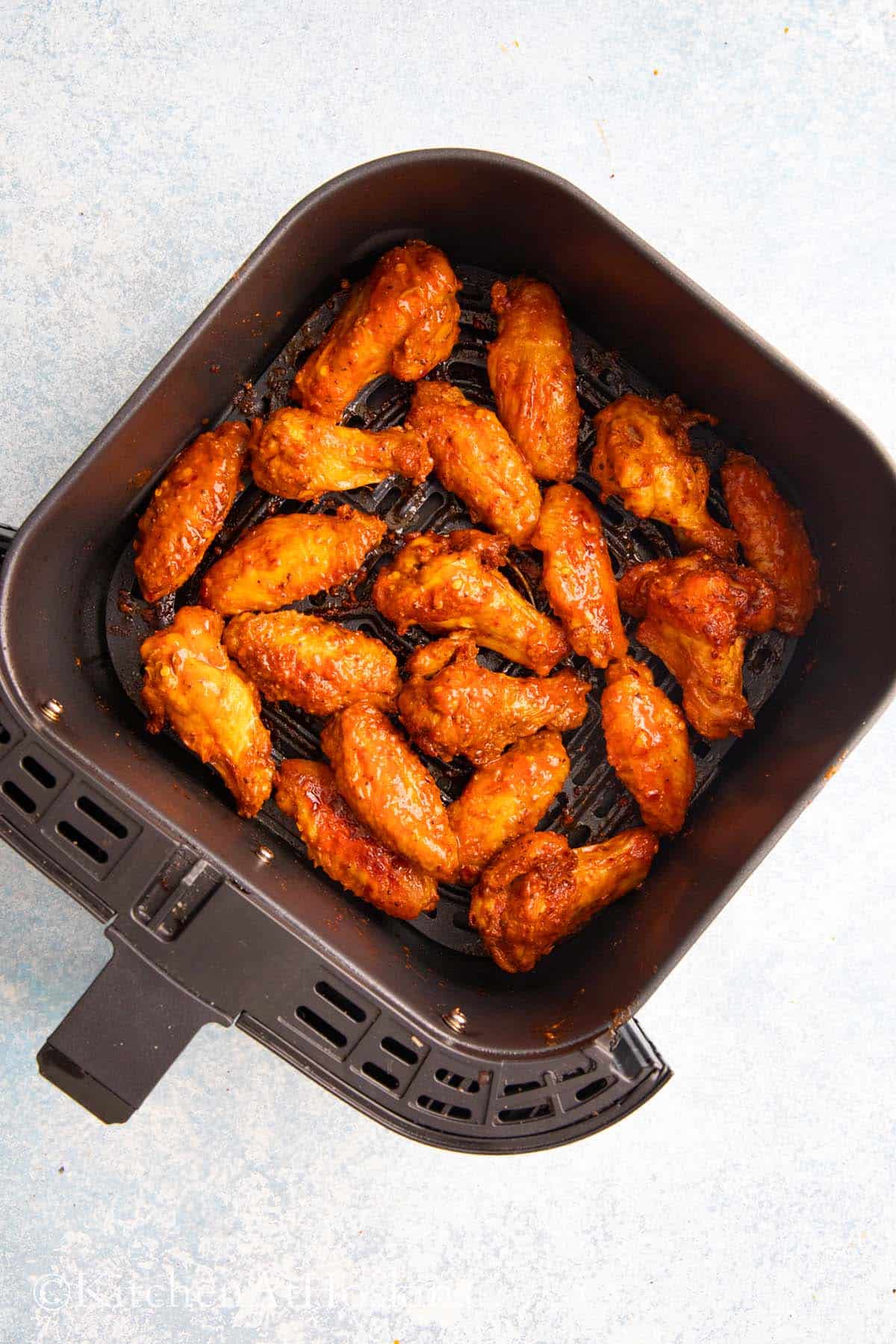 spicy hot wings in a air fryer basket.