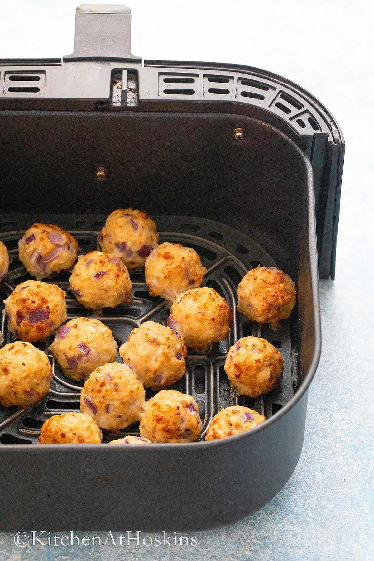cooked chicken meatballs in an air fryer basket.