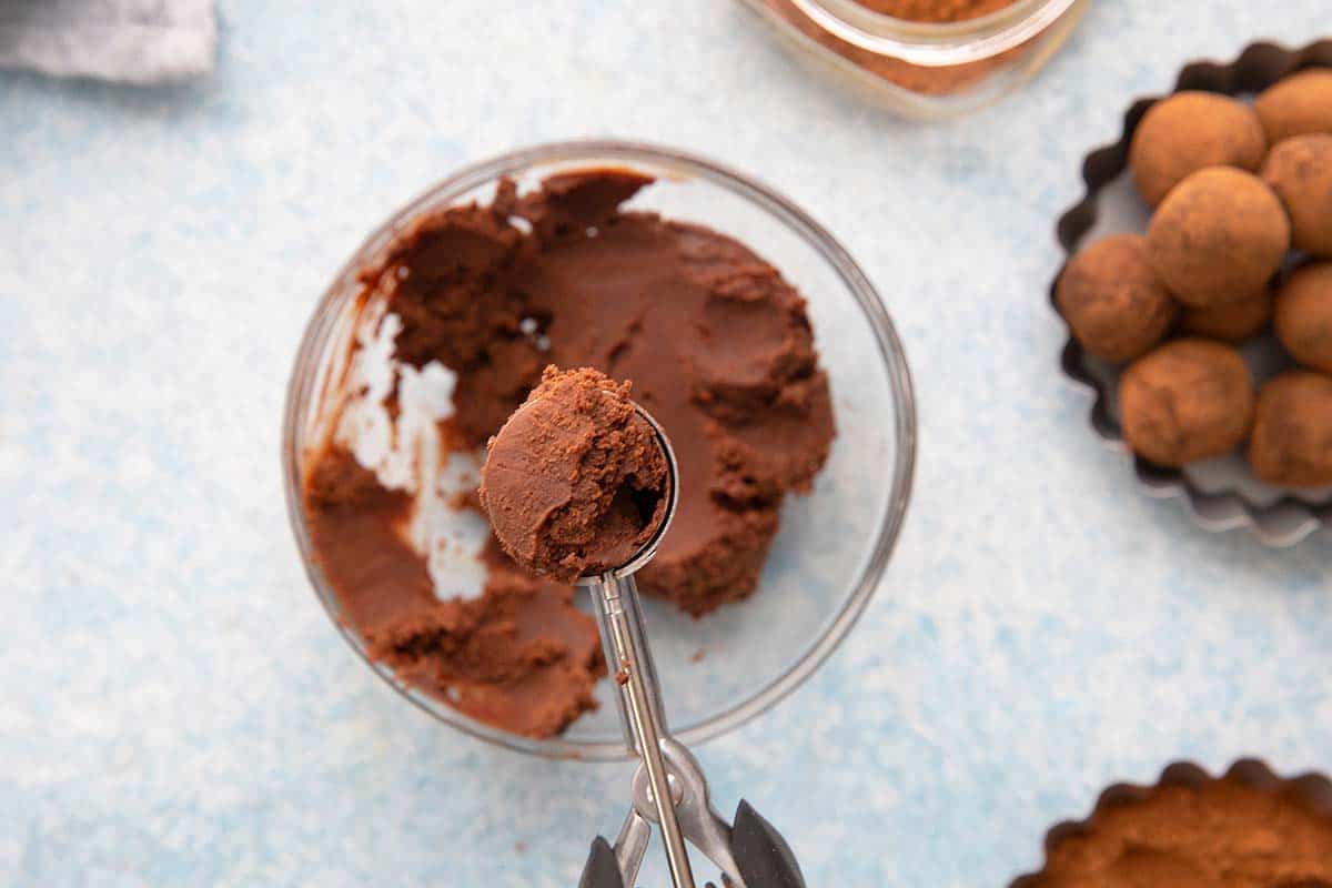 scooping some truffle dough using an ice cream spoon.