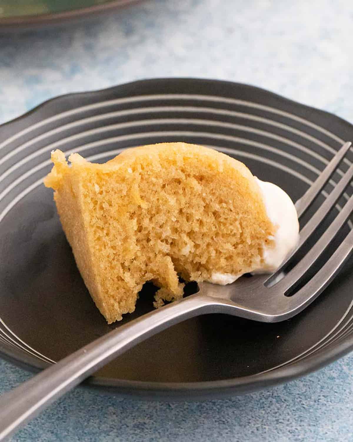a small piece of brown almond flour cake in a small black plate along with a fork.