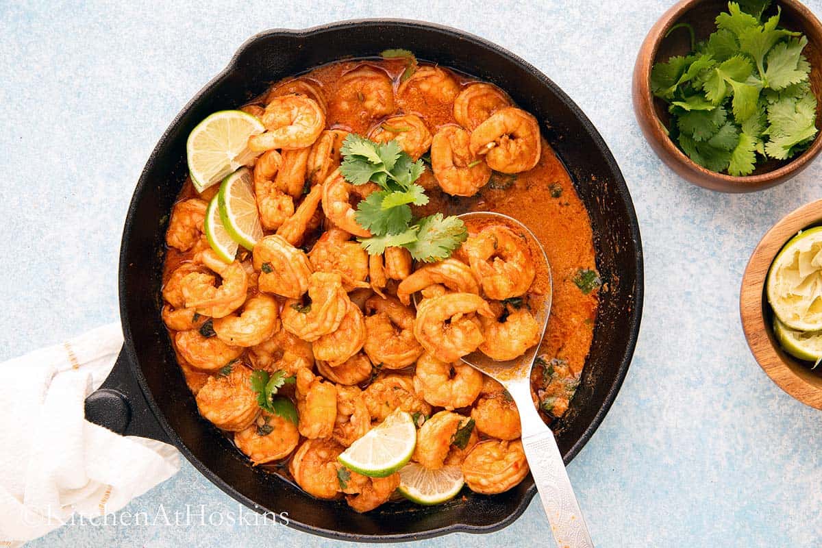 spoon with cooked shrimp in a chili lime sauce.