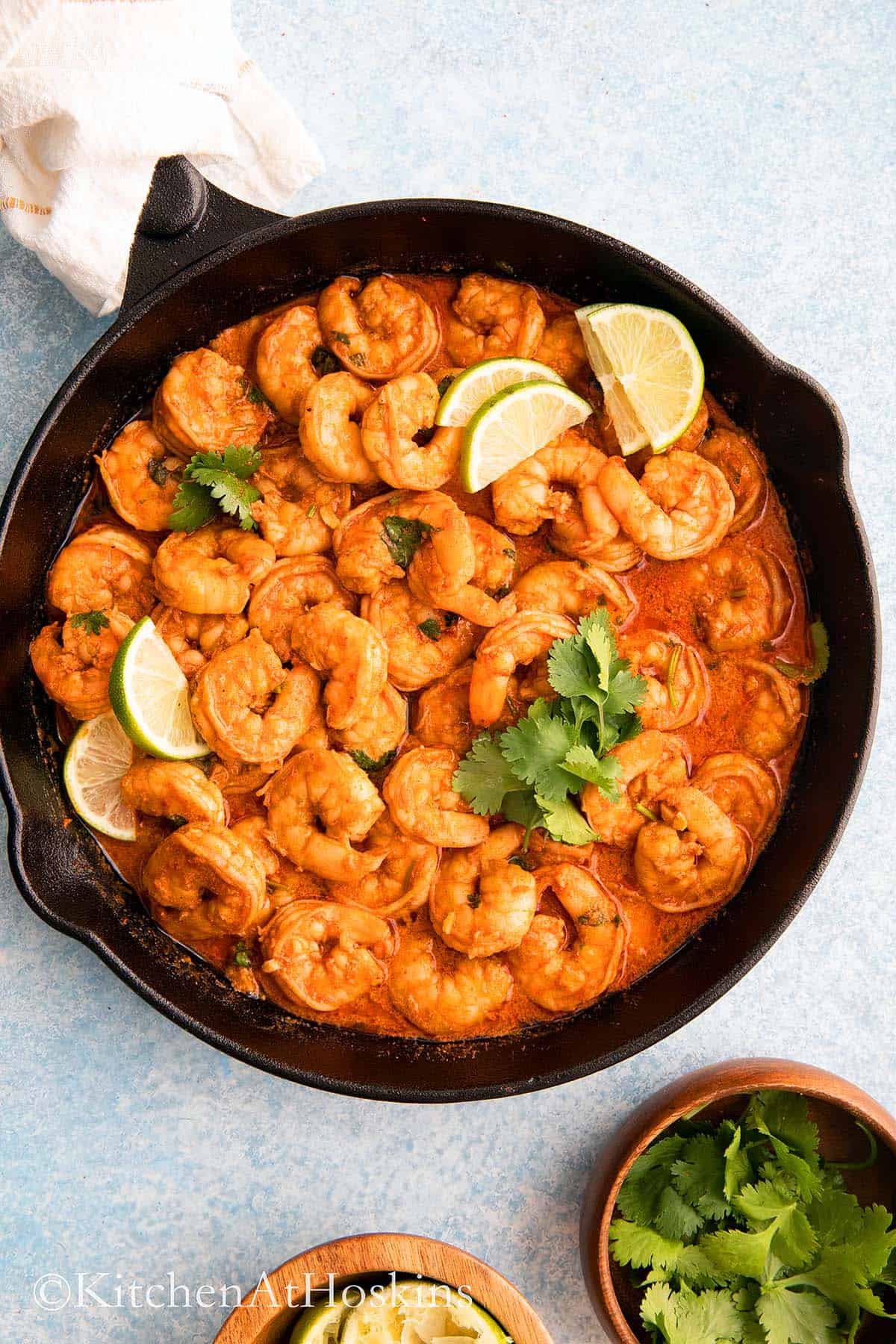 spicy shrimp in a skillet garnished with lime and cilantro.