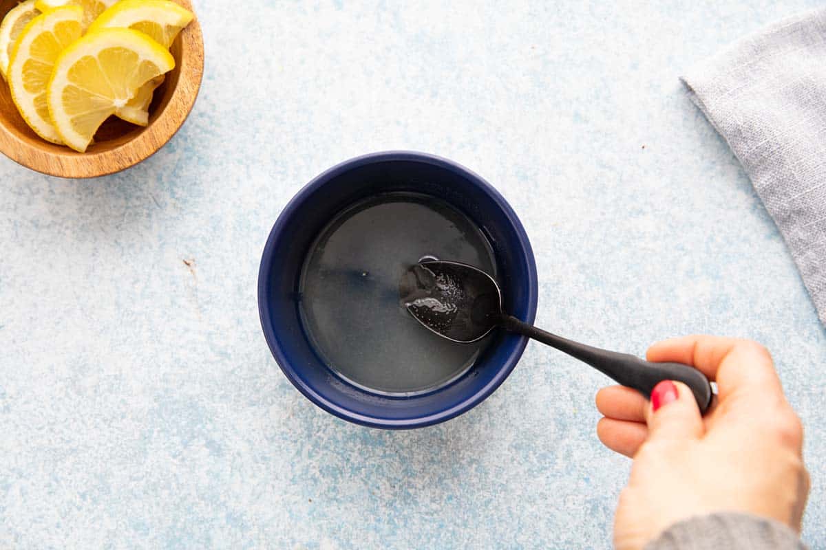 stirring lemon juice and sugar in a blue bowl. 